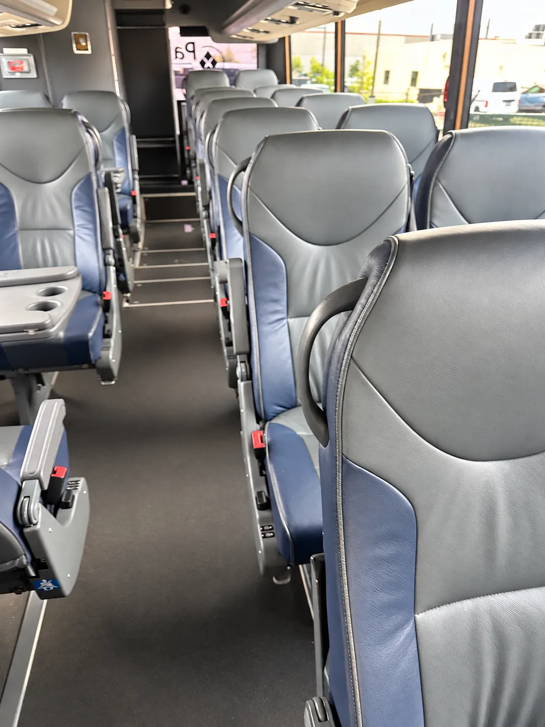 Seatback tray tables with built-in cupholders between passenger rows in the Four Season Travel Mini Coach