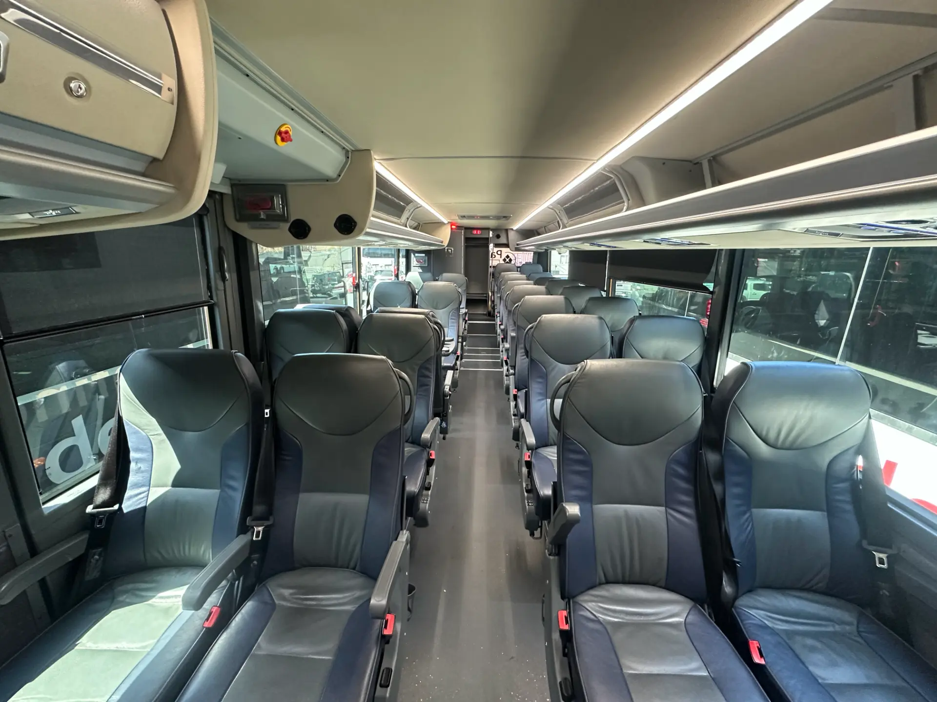 Wide view of the Four Season Travel Mini Coach passenger cabin with high-back seats, seatbelts, a center aisle, overhead storage, and ceiling lighting